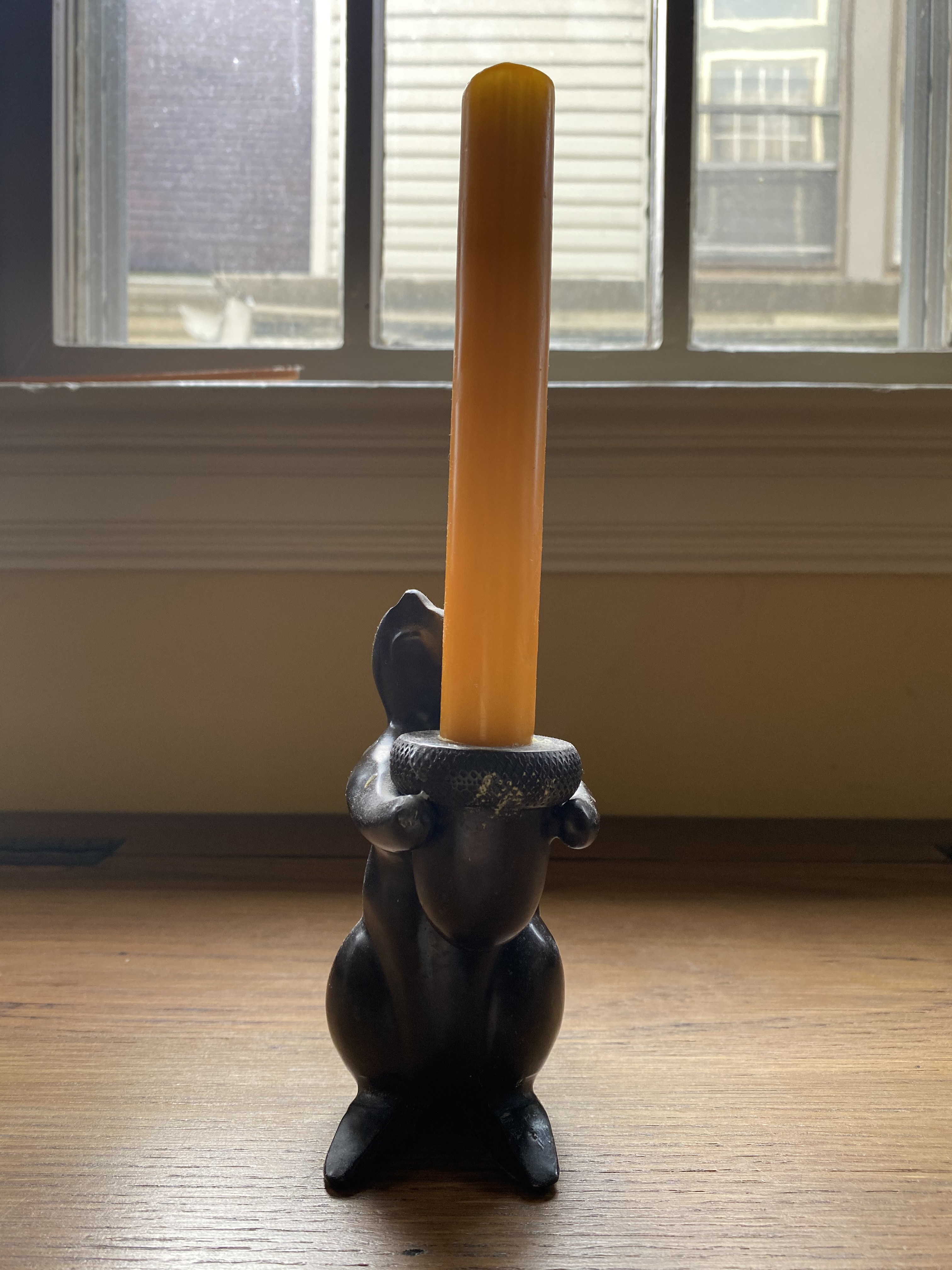 the front of a squirrel candle holder, the squirrel holds an acorn, out of which a candle grows. the squirrel gazes up at the candle