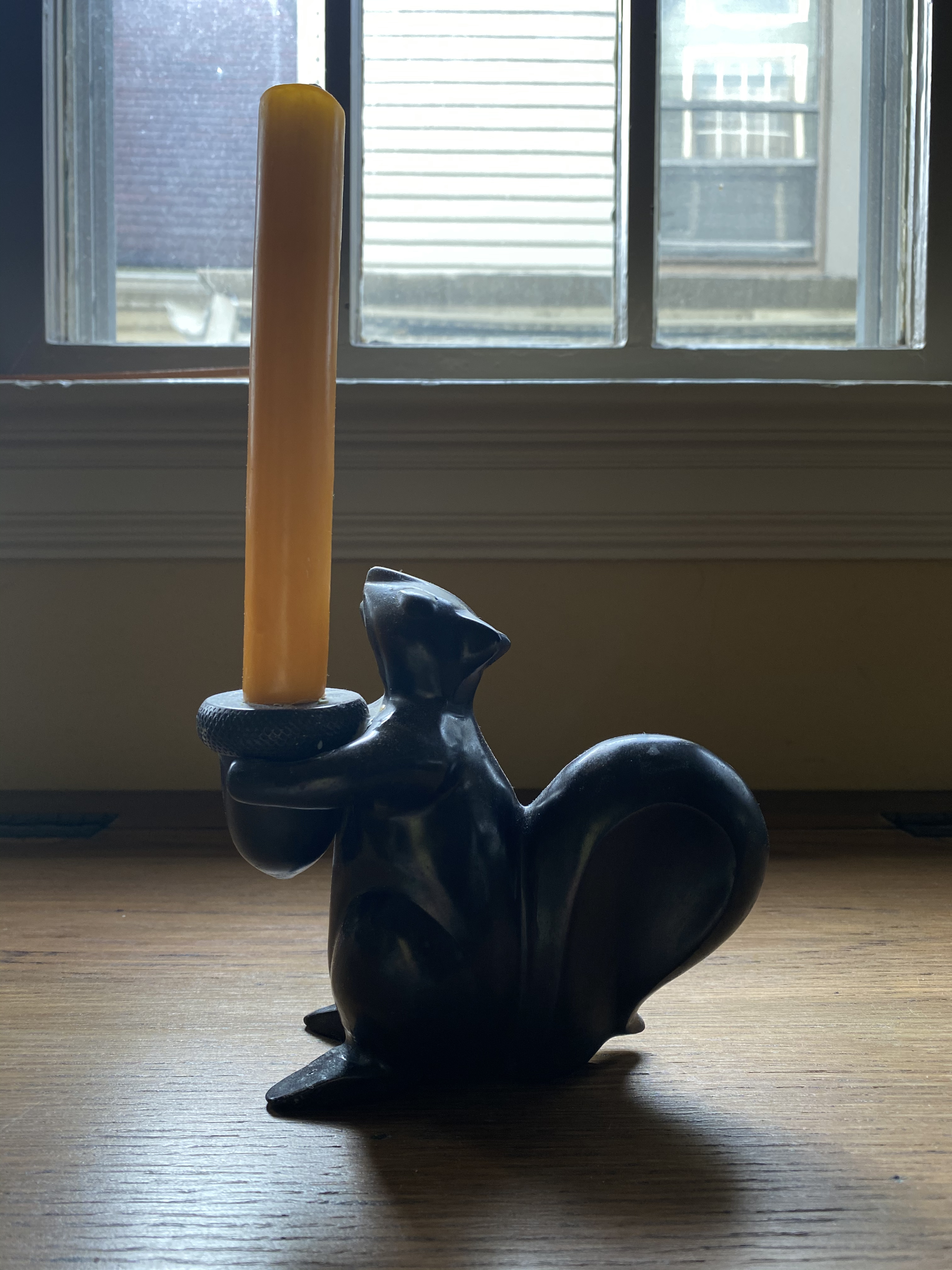 the left of the squirrel, similar to the right. remains of past candles that have dripped over the acorn are visible, but minor. the last candle stick was forrest green